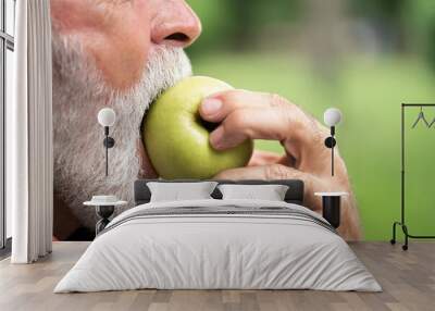 Senior sportsman eating green apple Wall mural