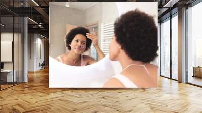 Woman checking her hair in bathroom mirror at home Wall mural