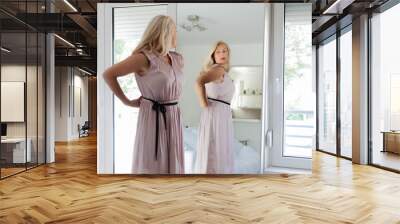 Woman standing in dress in front of mirror Wall mural