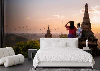 Bagan Myanmar, a couple of men and women are looking at the sunrise on top of an old pagoda temple. a couple on vacation in Myanmar Asia visit the historical site of Bagan with hot air balloons  Wall mural