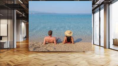 Two friends enjoy a peaceful day at the beach on Brac Island, admiring the clear blue waters and serene surroundings. a diverse couple on the Zlatni Rat Beach Wall mural