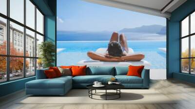 Young Asian women on vacation at Santorini relaxing in swimming pool looking out over Caldera ocean Wall mural