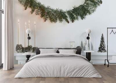 Christmas composition on the white chimney at the living room interior with beautiful decoration. Christmas tree and wreath, candles, stars, light. Copy space. Template. Wall mural