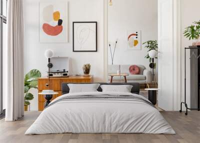 Elegant and retro decor of living room with design commode, coffee table vinyl recorder, cacti and mock up posters frames on the white walls.  Stylish room with brown wooden parquet and plants. Wall mural