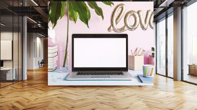 Modern creative desk with laptop mock up screen, books, office accessories, elephant figure, plant, tropicla leaf. Concept of mock up laptop screen. Pink background wall. Love inscription. Wall mural