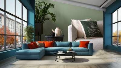 Stylish composition of living room interior. Modern sofa, design pillows, plants in metal pot and creative personal accessories. Eucalyptus green wall. Template. Copy space. Wall mural