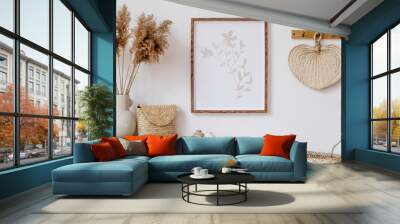 Stylish korean interior of living room with brown mock up poster frame, elegant accessories, flowers in vase, wooden shelf and hanging rattan leaf. Minimalistic concept of home decor. Template.  Wall mural