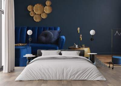 Stylish modern living room interior design with glamour blue velvet sofa, pouf, golden metal side table and modern home accessories. Dark blue wall. Template. Copy space. Wall mural