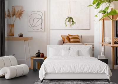 The stylish boho interior of living room at nice apartment with gray sofa, wooden desk, bamboo shelf, coffee table,  honey yellow pillows, plants and elegant accessories. Mock up paintings on the wall Wall mural