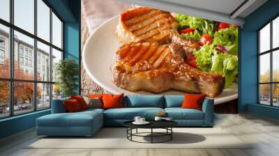 Barbecue food: a grilled pork chop in sweet honey glaze and a salad of fresh vegetables close-up on a plate on a table. horizontal Wall mural