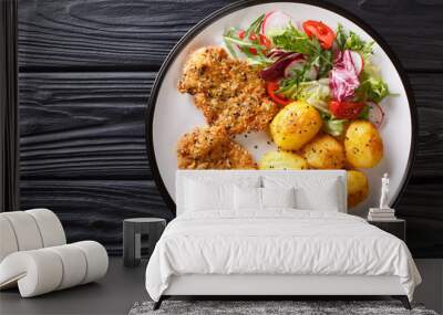 Crispy steaks in sesame breading with new potatoes and fresh salad close-up on a plate. horizontal top view Wall mural