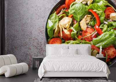 Delicious healthy salad of artichoke hearts, tomatoes, spinach, arugula, fried peppers and onions close-up in a plate on the table. Horizontal top view from above Wall mural