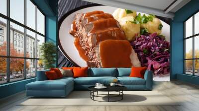 Delicious traditional German dinner Sauerbraten - slowly stewed marinated beef with gravy with potato dumplings and red cabbage close-up. horizontal Wall mural