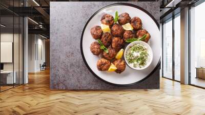 Keftedakia is a Greek traditional dish that is created with minced beef and bread crumbs rolled into balls and fried closeup on a white plate on a table. Horizontal top view from above Wall mural