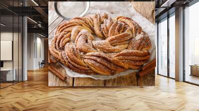 Kringle tasty Estonian, Czech and Skandinavian dessert with cinnamon closeup on the paper on the wooden table. Horizontal Wall mural