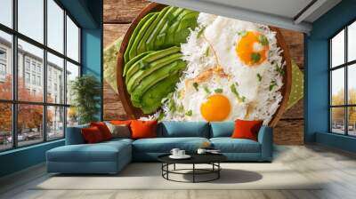 Latin American food of boiled rice and fried eggs close-up in a plate on the table. horizontal top view from above Wall mural