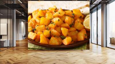 Lebanese spicy potatoes are traditionally known as batata harra close up in the plate on the table. Horizontal Wall mural