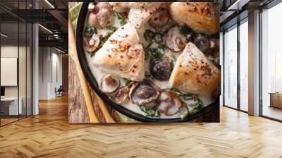 Pieces of chicken with wild mushrooms and spinach in a creamy sauce close-up on a table. Vertical top view Wall mural