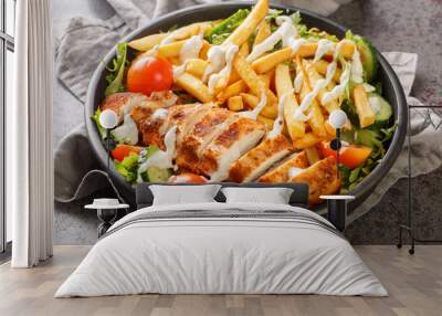 Pittsburgh steak salad consists of a bed of lettuce that's topped with tomatoes, cucumbers, a piece of grilled chicken, and crispy french fries closeup on the bowl on the table. Horizontal Wall mural