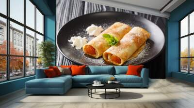 Portion of delicious crepes with apricot filling and powdered sugar close-up in a plate on the table. horizontal Wall mural