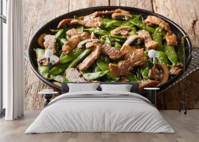 Stir-fried meat with mushrooms and pea pods, garlic, sesame seeds in soy sauce close-up in a plate on the table. horizontal Wall mural