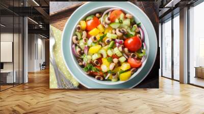 Summer salad with cherry tomatoes, celery, yellow pepper, black-eyed peas, cucumber and onion close-up in a bowl on a wooden board. horizontal top view from above Wall mural