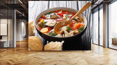 Thick tomato fish soup with eel and vegetables closeup in a bowl served with bread. horizontal Wall mural