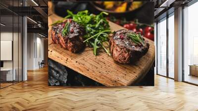 Grilled fillet steaks on wooden cutting board. Succulent thick juicy portions of grilled fillet steak served with tomatoes and roast potatoes on an old wooden board. Wall mural