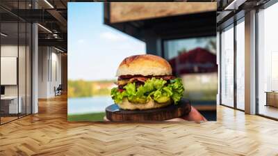 Juicy tasty cheeseburger with beef, lettuce, pickles, tomato and onion rings on a wooden table. Classic street food - grilled burger Wall mural