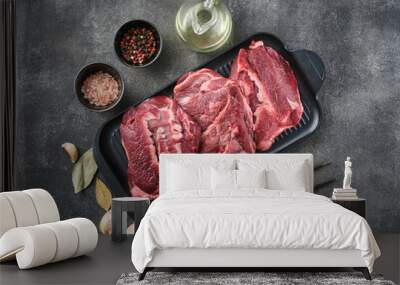 Raw pork cheeks meat on a dark gray surface with spices. Top view Wall mural