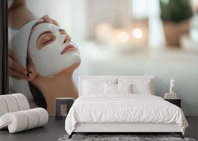 A beautician applying a white clay mask to the face of a beautiful young woman in a beauty salon, emphasizing spa treatments and relaxation. photo Wall mural