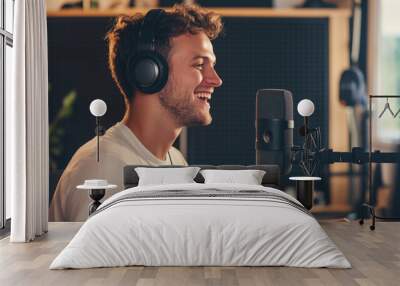 A cheerful young man wearing headphones, passionately speaking into a microphone in a dynamic podcast studio setting. The vibrant background highlights his enthusiasm and energy fo Wall mural