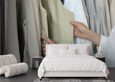 Close-up of female hands plucked hanger choosing clothes in clothing store. Middle aged woman runs across a rack of clothes in a shopping mall. Sale promotion and shopping concept. Part of the series. Wall mural