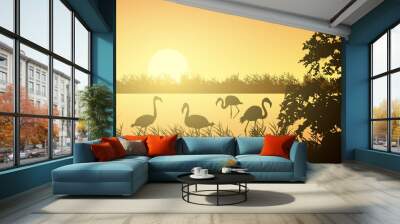 Realistic illustration of wetland landscape with river or lake, water surface and birds. Flamingo and stork flying under orange morning sky with rising sun, vector Wall mural