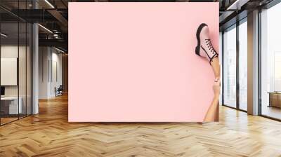 Fashionable pink boots on slim woman legs on pastel pink background with free place for text. Wall mural