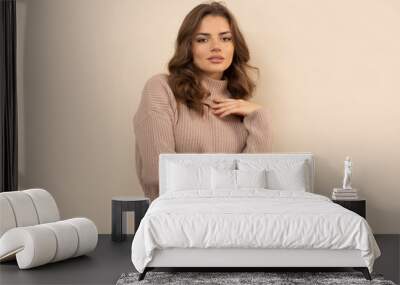 Studio shot of attractive young woman in brown sweater on brown background. Wall mural