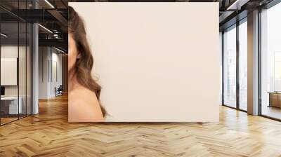 Very attractive young woman with curly brown hairs on light brown background. Wall mural