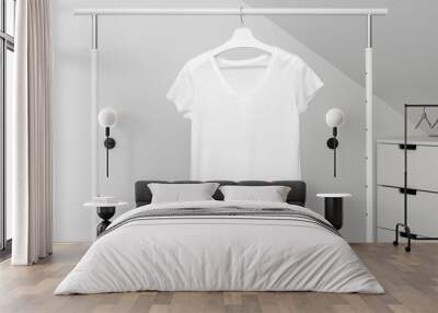 Group of Assorted t-shirts hanging on white hangers. Clothing rack Wall mural