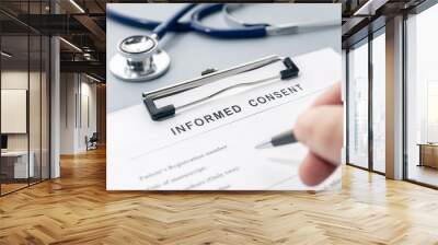 Hand filling a Informed Consent form and stethoscope on desk Wall mural