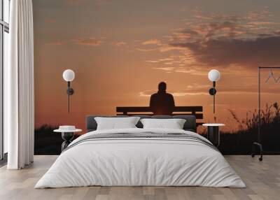 A man sits on a bench in the evening, watching the sun set Wall mural