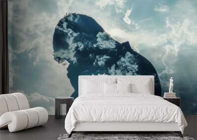 A person praying in front of a cloudy sky Wall mural