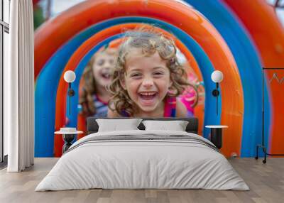 Two young girls are smiling and laughing as they play on a slide Wall mural