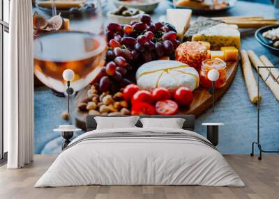 Wooden board with different kinds of cheese and glass of rose wine. Dinner or aperitivo party concept. Wall mural