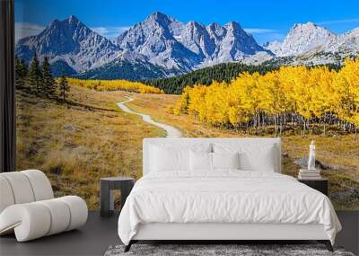 A scenic landscape featuring a winding trail, vibrant yellow trees, and majestic mountains under a clear blue sky. Wall mural