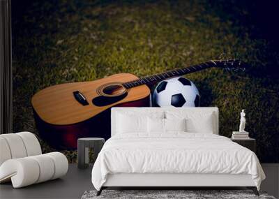 Guitar and football are placed in green lawns. Music and sports ideas And there is a copy space. Wall mural