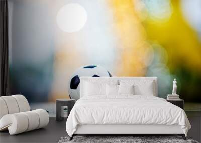 The soccer ball is placed on a wooden floor and has a blurred background with beautiful bokeh. Wall mural