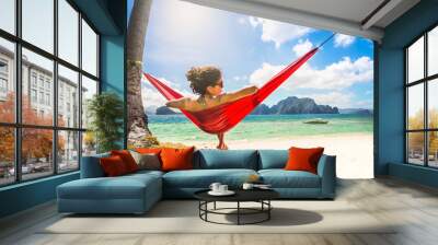 Young caucasian female relaxing in a red hammock on a tropical b Wall mural