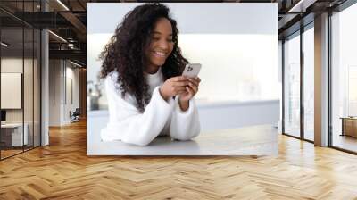 African American smiling Girl using smartphone on modern kitchen at home, pressing finger, reading social media internet, typing text or shopping online, Mobile phone in two black hands Wall mural