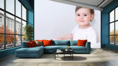 Portrait cute baby girl on kitchen sitting on high chair, smiling child happy to eat first solid food. Wall mural