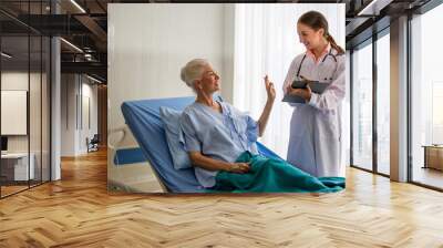 doctor talking to senior patient sitting on a bed in hospital Wall mural